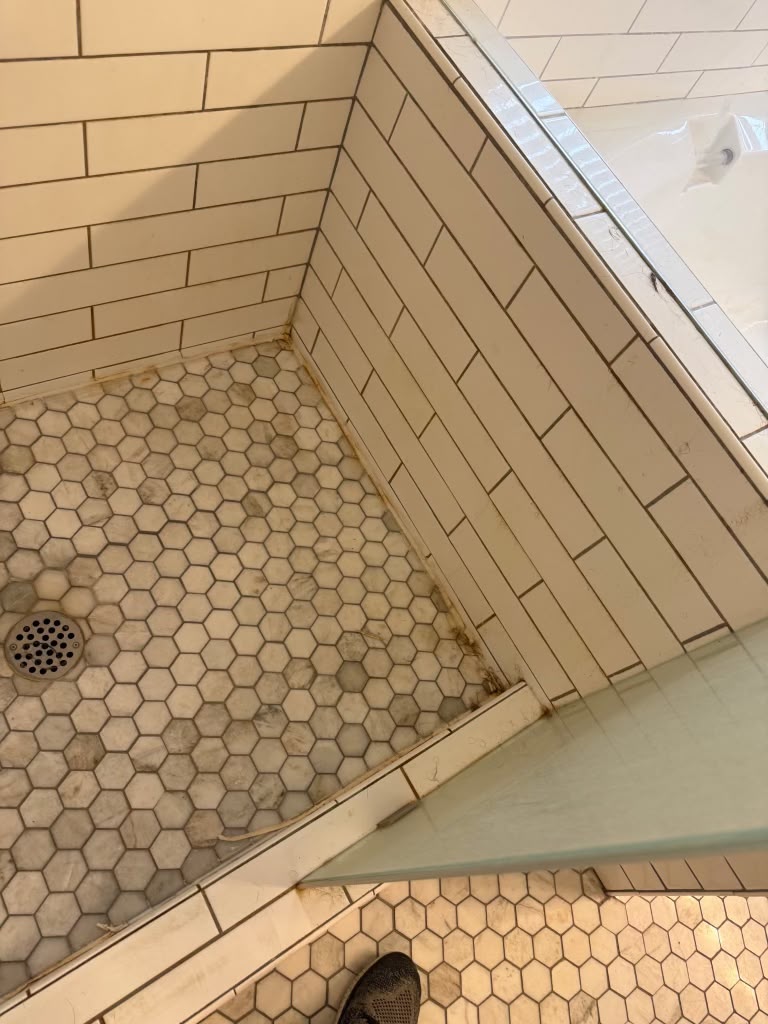 Shower floor and tile with grime buildup before cleaning